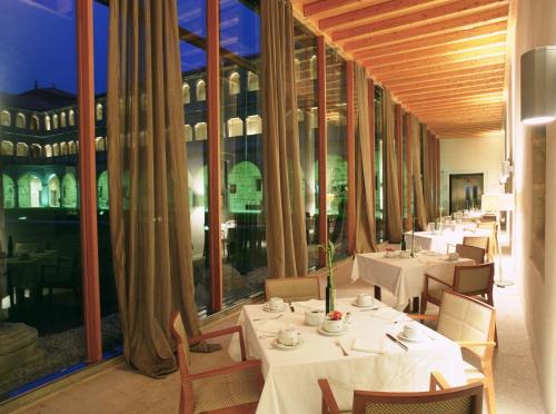 Un restaurante con mesas y sillas blancas y grandes ventanales. en Parador de Santo Estevo, en Santo Estevo de Rivas de Sil