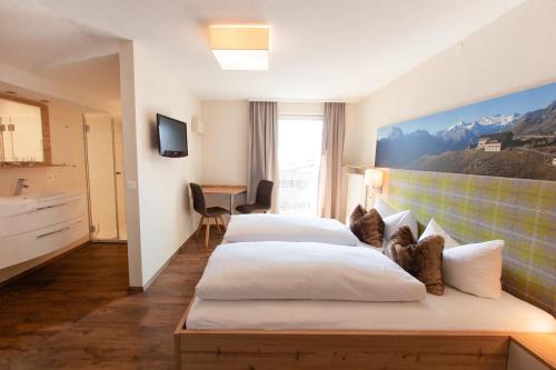 フルプメスにあるPension Gletscherblickのベッド2台とデスクが備わるホテルルームです。