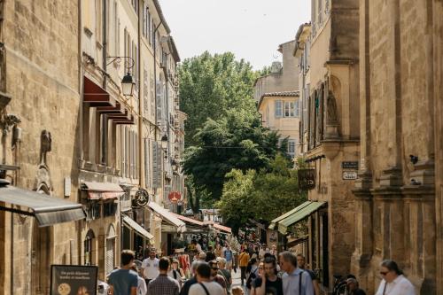 a crowd of people walking down a street with buildings at Hôtel Boutique Cézanne centre Aix-en-Provence in Aix-en-Provence