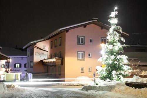 a christmas tree covered in snow in front of a building at Pension Gletscherblick in Fulpmes