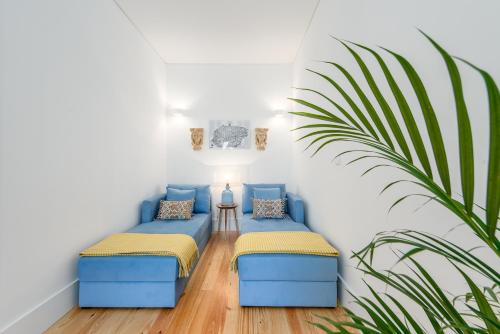 two blue couches in a room with a plant at Porto Belo Sao Bento Apartment in Porto