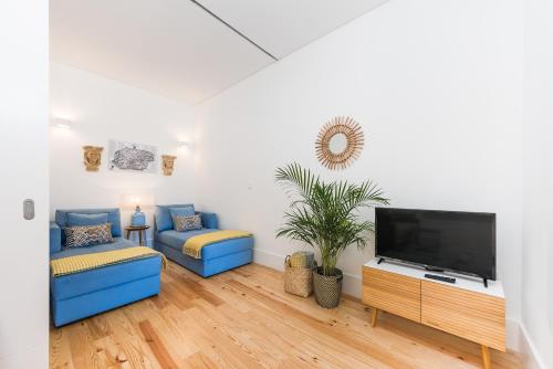 a living room with a blue couch and a flat screen tv at Porto Belo Sao Bento Apartment in Porto