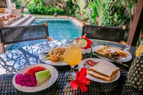a table with plates of food next to a swimming pool at Desa Di Bali Villas in Kerobokan