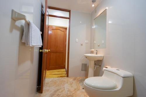 biała łazienka z toaletą i umywalką w obiekcie Hawka Inka Hostal - Cusco w Cuzco
