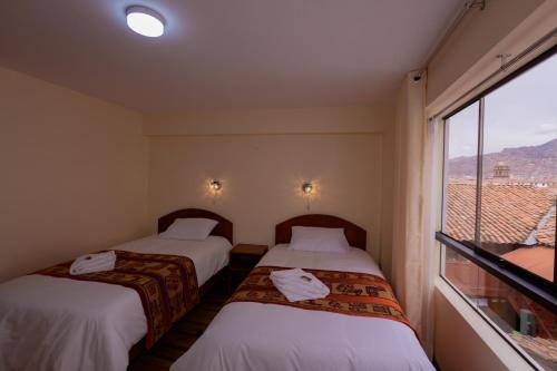 dwa łóżka w pokoju z oknem w obiekcie Hawka Inka Hostal - Cusco w Cuzco