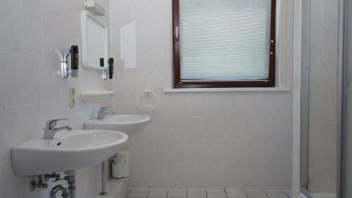 a white bathroom with two sinks and a shower at Entrée Hotel Glinde in Hamburg