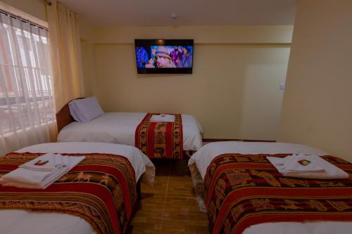 a room with three beds and a tv on the wall at Hawka Inka Hostal - Cusco in Cusco