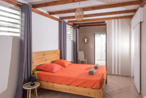 une chambre avec un lit avec un couvre-lit orange dans l'établissement Villa Cosy - Grande capacité avec piscine, au Gosier