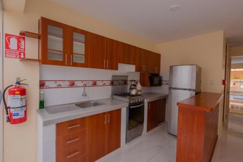 a kitchen with wooden cabinets and a stainless steel refrigerator at Hawka Inka Hostal - Cusco in Cusco