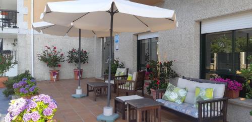 un patio con sombrilla, sillas y flores en Hotel Cachada, en Sanxenxo