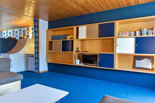ein Wohnzimmer mit blauem Teppich und Holzschränken in der Unterkunft Chesa Flurina - Celerina in Celerina