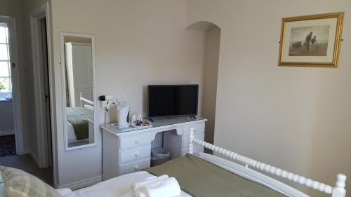 a bedroom with a tv on a white dresser at Central Bar Guesthouse in Cushendall
