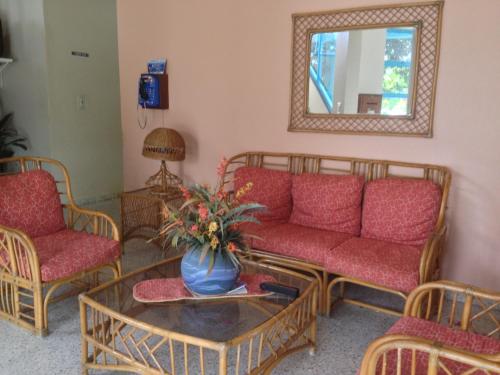 a living room with red couches and a table and a mirror at Hotel Caribe in Santa Cruz de Barahona