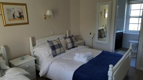 a bedroom with a white bed with a blue blanket at Central Bar Guesthouse in Cushendall