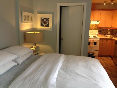 a bedroom with a white bed and a kitchen at Studiotel Bromont in Bromont