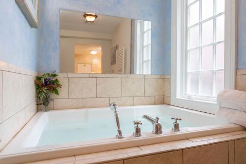 a bath tub with a window and a mirror at The Villa Bed and Breakfast in Westerly