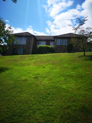 a house with a grassy yard in front of it at Highridge Apartment in Wooler