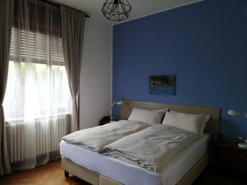 a bed in a blue bedroom with a window at La Tana Rooms in Lenno