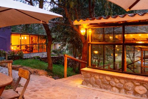 a house with an umbrella and a table and chairs at Casa de La Chola in Ollantaytambo