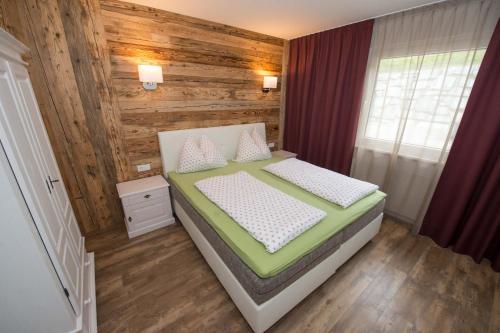 a bedroom with a bed and a wooden wall at Appartements Herwig Schwarzenbacher in Weissensee