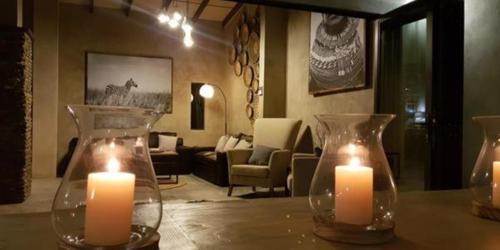two candles in vases on a table in a living room at Dream of Africa Bush Lodge in Marloth Park