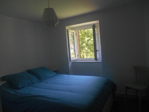 une chambre avec un lit bleu et une fenêtre dans l'établissement Appartement Vallée de Luchon, à Salles-et-Pratviel