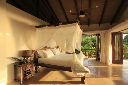 a bedroom with a bed with a mosquito net at Villa Numu in Mal País
