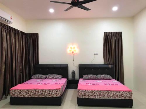 2 bedden in een slaapkamer met roze lakens en een plafondventilator bij Family Homestay in Taiping