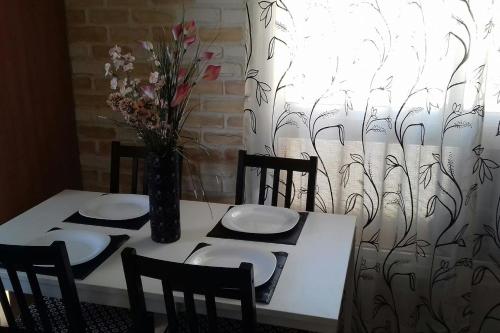 una mesa con sillas y un jarrón con flores. en Casa San Miguel free WiFi, en Morro del Jable