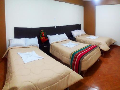 two beds in a room with a christmas tree between them at Kantu Progreso Inn in Cusco