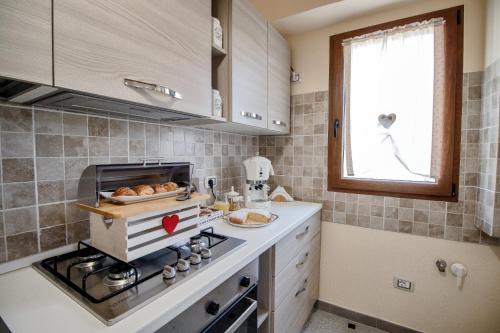 a kitchen with a stove and a window at Il giardino degli ulivi in Santa Maria Coghinas