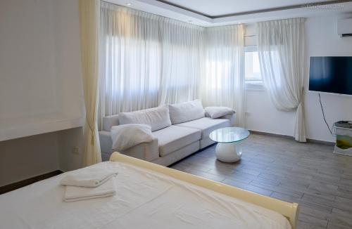 een witte woonkamer met een bank en een tv bij Royal Lea Apartmens in Netanya