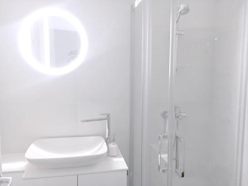 a white bathroom with a sink and a shower at NEW Central Light Apartment with Private Parking in Novi Sad