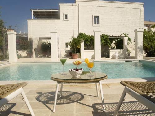 a table with drinks and fruit on it next to a pool at Masseriola Antiche Fogge in Fasano