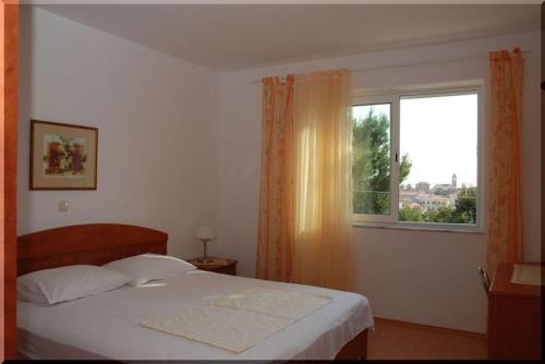 a bedroom with a large bed and a window at Apartmani Ivić Paka Rab in Banjol