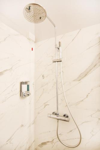 a shower in a bathroom with white marble walls at LA QUADRA SUITES - Central Apartments in Iseo with daily housekeeping in Iseo
