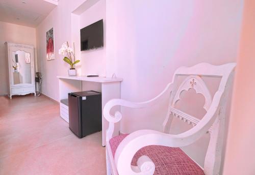 Cette chambre rose comprend une chaise blanche et un bureau. dans l'établissement Villa Giardini Luxury Room, à Capri