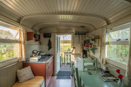 a kitchen and dining room in a tiny house at Pipowagen Lidewei Groningen Westerwolde unieke ligging met eigen tuin en vrij uitzicht over veld naar natuurgebied in Onstwedde