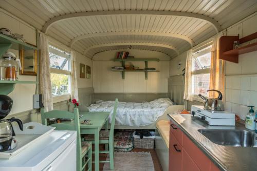 a small kitchen with a bed in a tiny house at Pipowagen Lidewei Groningen Westerwolde unieke ligging met eigen tuin en vrij uitzicht over veld naar natuurgebied in Onstwedde