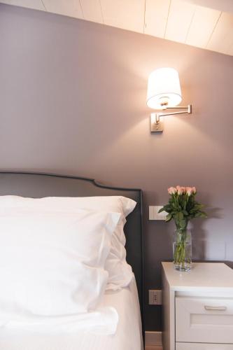 a bedroom with a bed and a lamp and a vase of flowers at LA QUADRA SUITES - Central Apartments in Iseo with daily housekeeping in Iseo