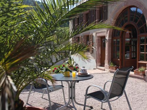 a patio with a table and chairs in front of a building at A l'ombre du verger in Breitenau