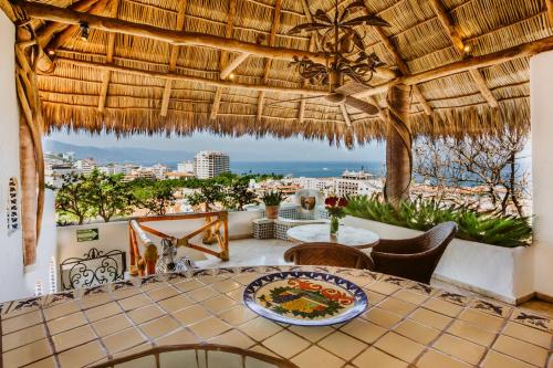 a patio with a table and chairs and a view of the city at Hacienda San Angel in Puerto Vallarta
