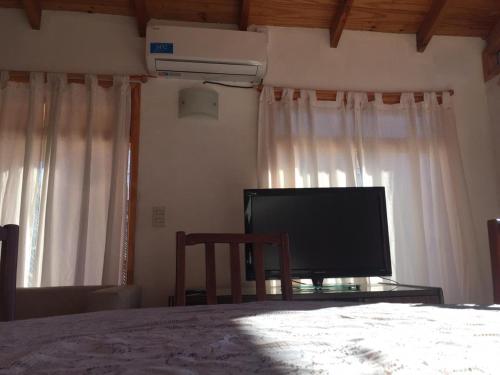 um quarto com uma cama e uma televisão de ecrã plano em La Casa de Belen em San Martín de los Andes