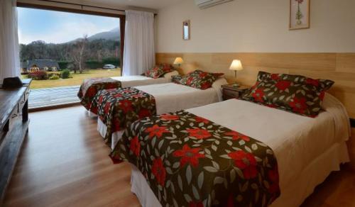 a hotel room with three beds and a window at La Estancia Cabañas in Villa La Angostura