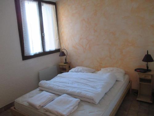 a bedroom with a bed with white sheets and a window at Central Parc in Briançon