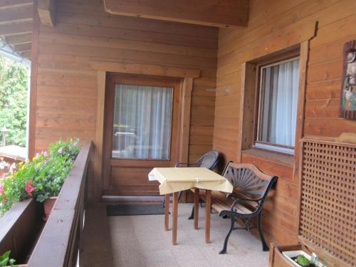 eine Veranda eines Holzhauses mit einem Tisch und Stühlen in der Unterkunft Apartmenthaus Rupitsch in Leutasch