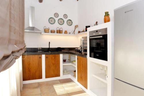 cocina con paredes blancas y armarios de madera en Suite in Masseria en Plemmirio