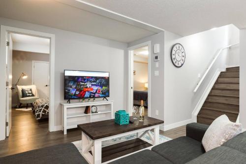 a living room with a couch and a tv at Modern Executive Suite I Complimentary Netflix & Parking! in Edmonton