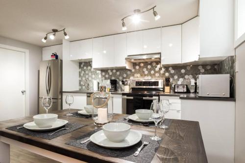 a kitchen with a table with plates and wine glasses at Modern Executive Suite I Complimentary Netflix & Parking! in Edmonton