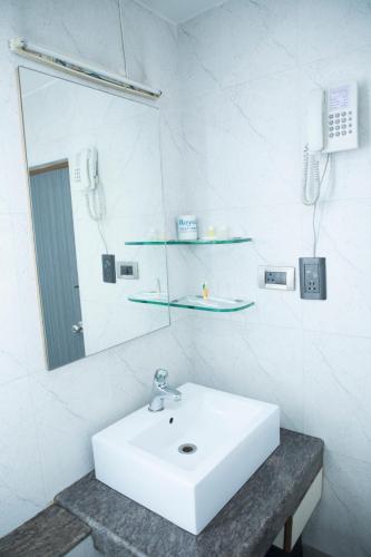 a white bathroom with a sink and a mirror at Moskva Hotel in Madurai